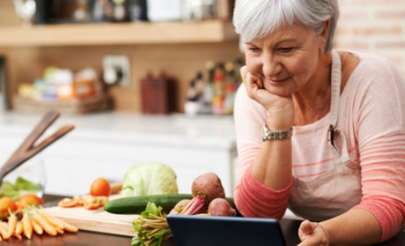 older adult watching tablet cooking