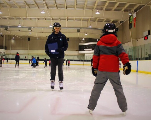 Skating instructor teaching little child