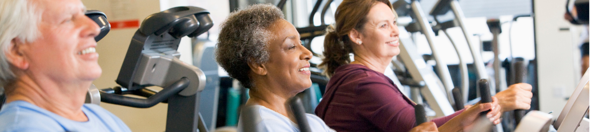 Men and women exercising on machines. 