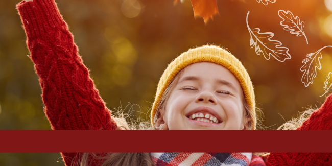 Close up of childs smiling face with a fall background