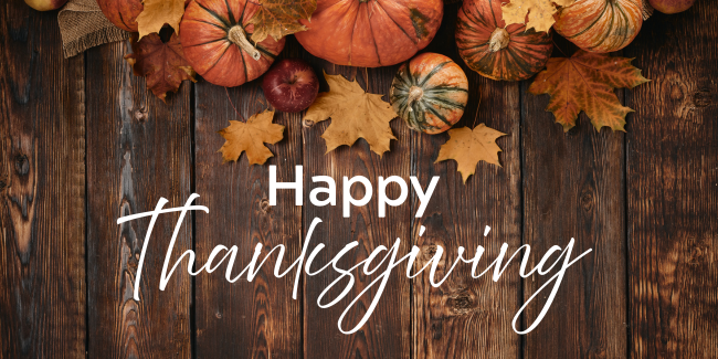 Brown wooden background with pumpkins and fall decorations across the top and Happy Thanksgiving written in white in the centre of the image