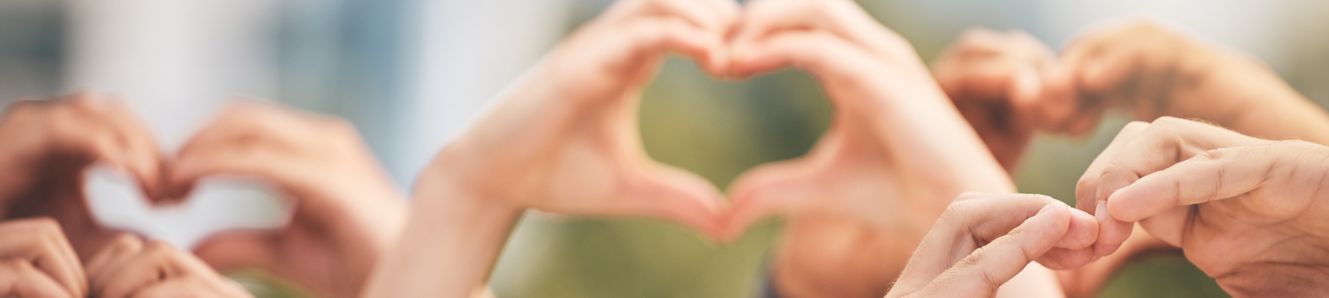 Various hands in the air, making heart shapes, slightly blurry