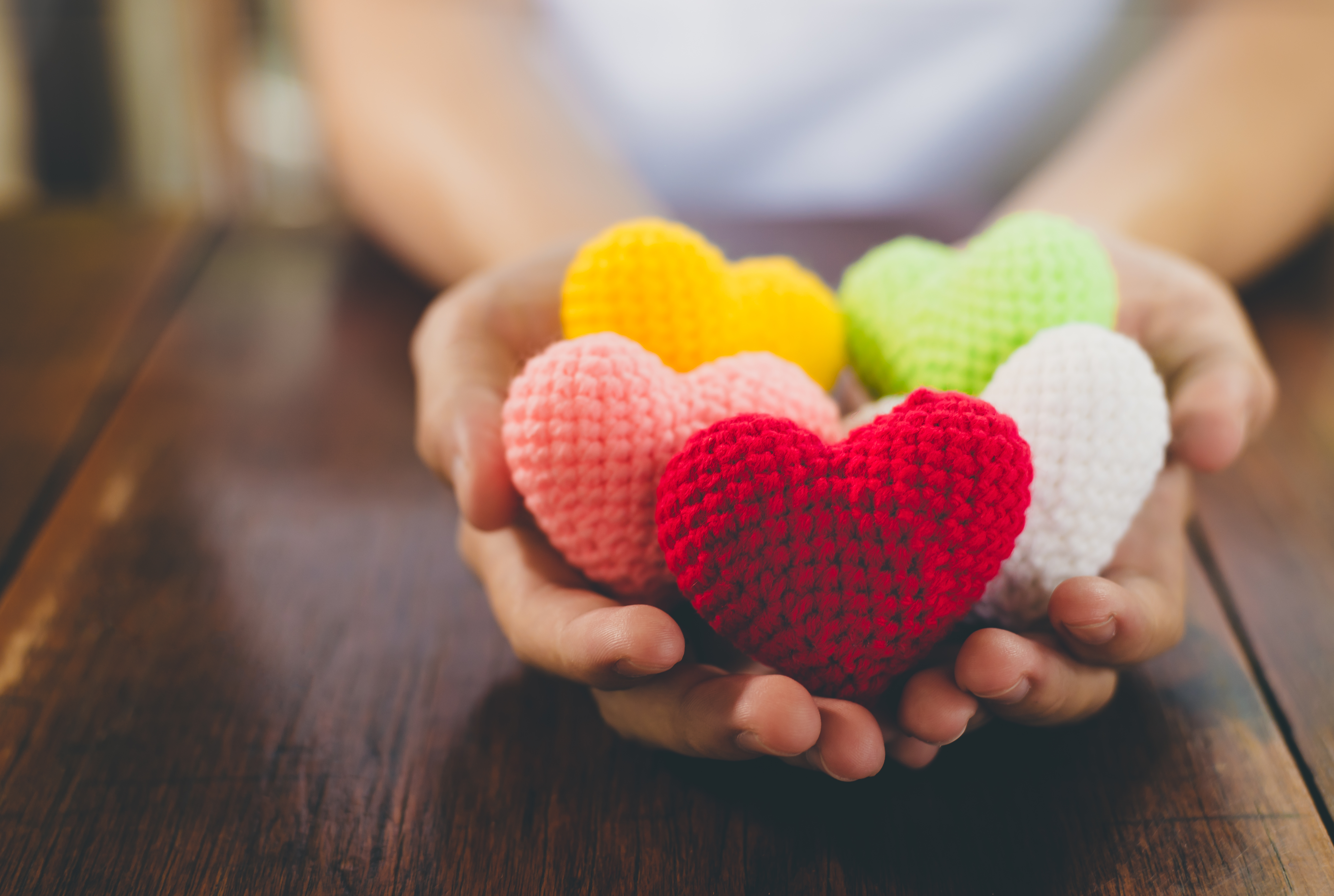 Hands holding a bunch of knitted hearts
